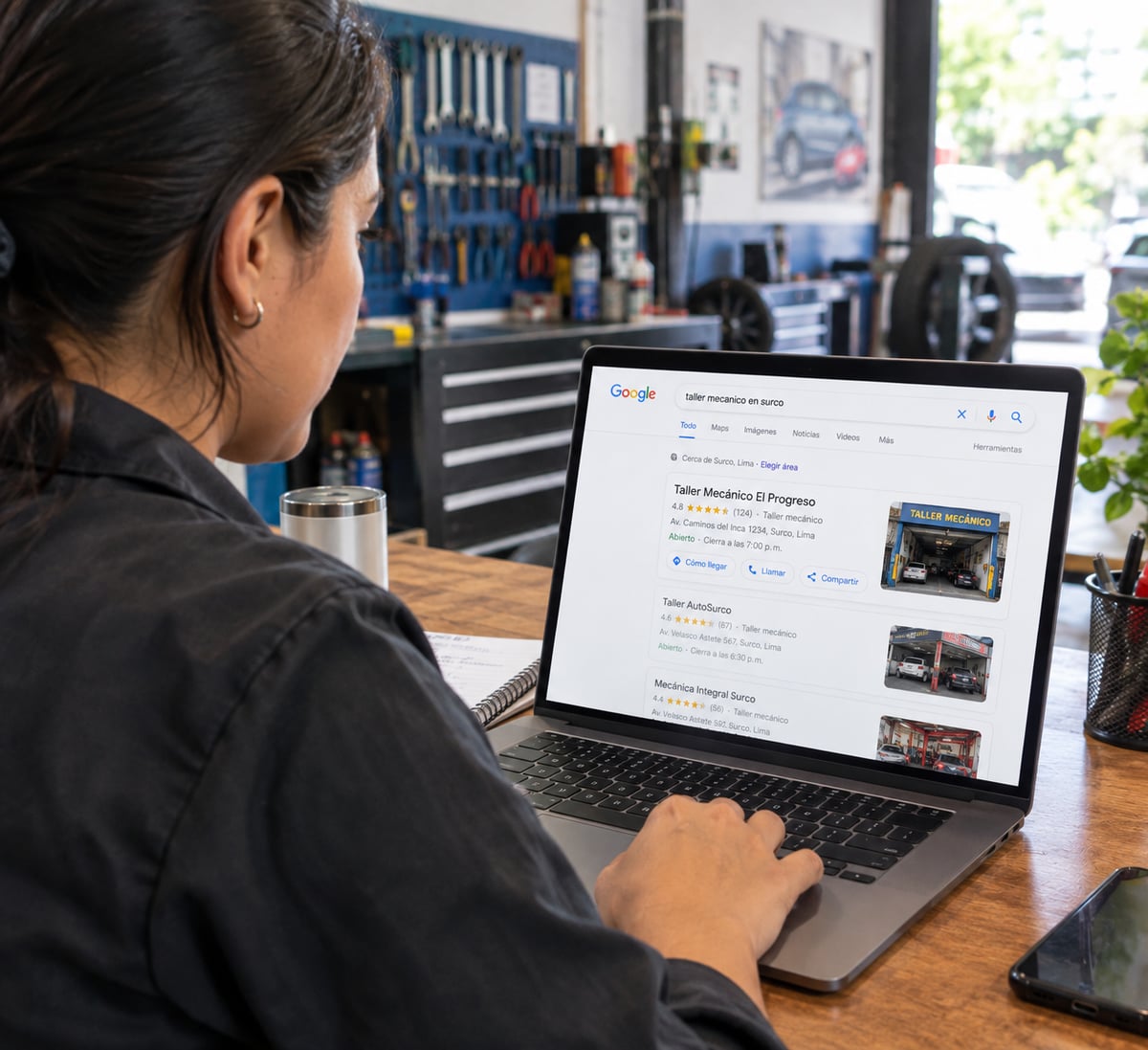 Dueño de un taller revisando en su laptop los resultados de búsqueda de Google donde aparece su negocio